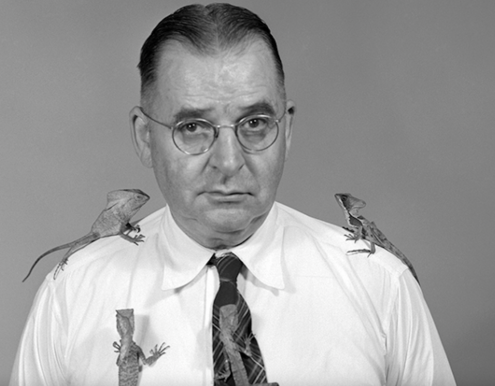 Black and white photo of man with lizards on shoulders